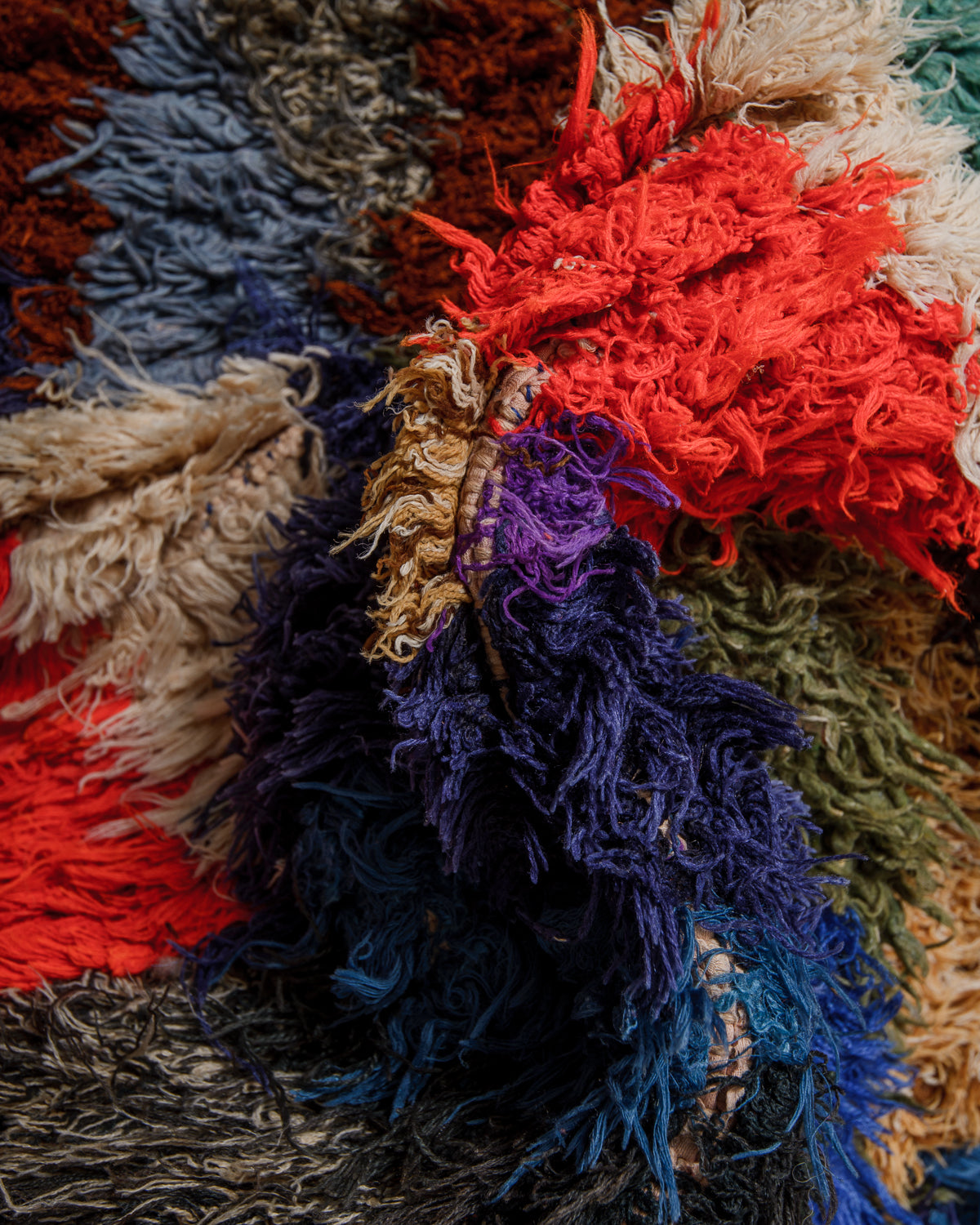 Close up showing cotton and fabric remnants, in shades of red, blue, white and green, used to make up this Boucherouite "rag rug".